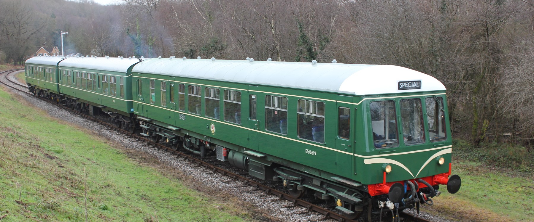 a train traveling down train tracks next to a green field