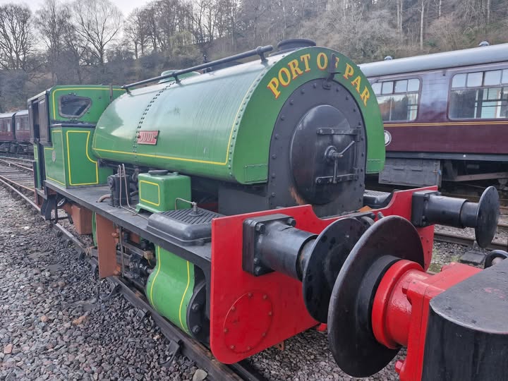 Green vintage steam locomotive with 'Port of Par' text on display.
